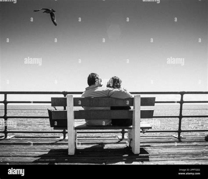 a man and woman sitting next to each other in front of a dark